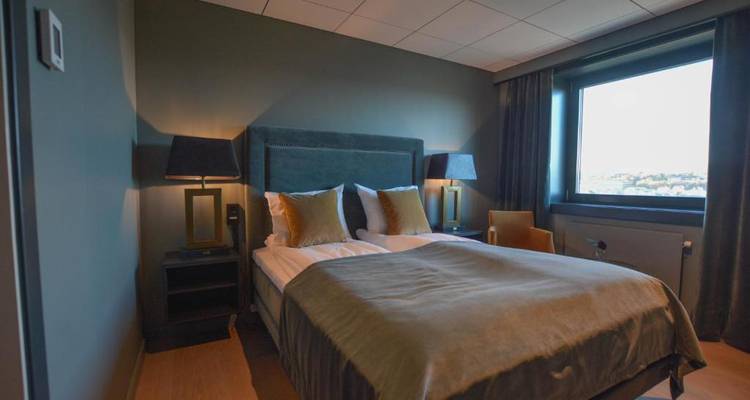 Chambre d'hôtel avec vue sur fenêtre, deux lampes et un grand lit.