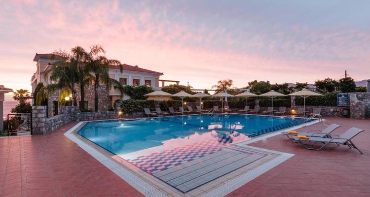 Zone de piscine d'hôtel au coucher du soleil avec un arrière-plan montagneux.