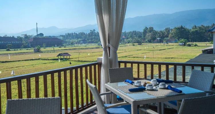 Outdoor dining area with a view of rice fields and mountains.