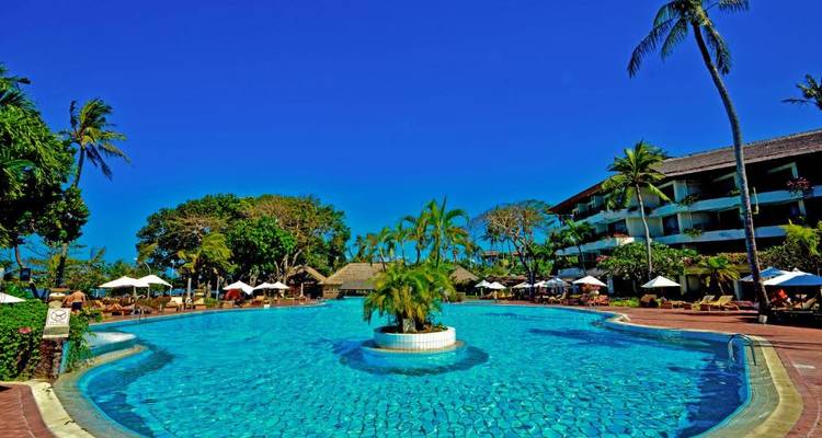 Resort pool area surrounded by trees and buildings.