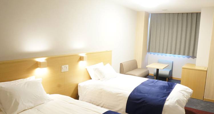 Habitación de hotel con dos camas individuales y zona de estar