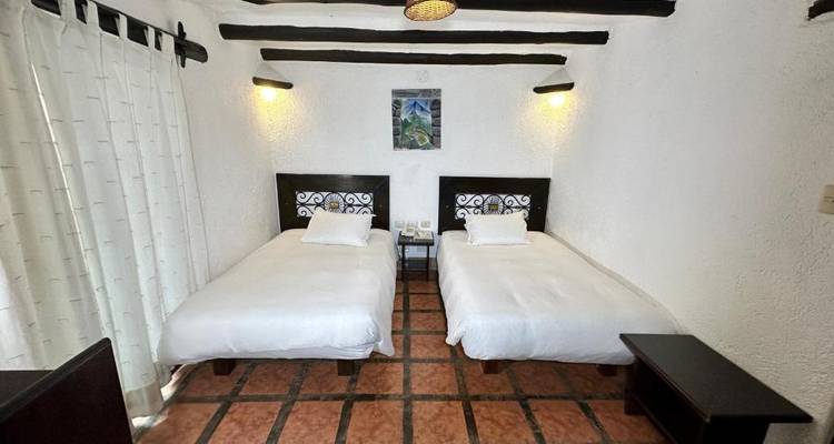 Habitación de hotel sencilla con dos camas individuales y mobiliario mínimo.