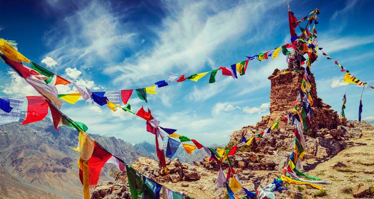 Banderas de oración coloridas en la cima de una montaña con un cielo dramático.