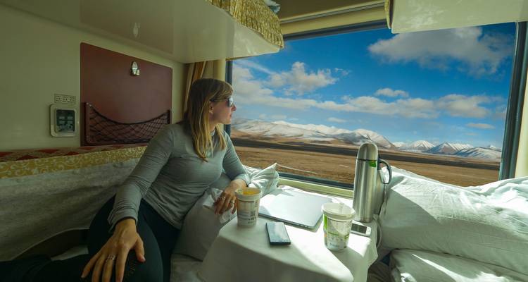 Mujer mirando las montañas desde un compartimento de tren.