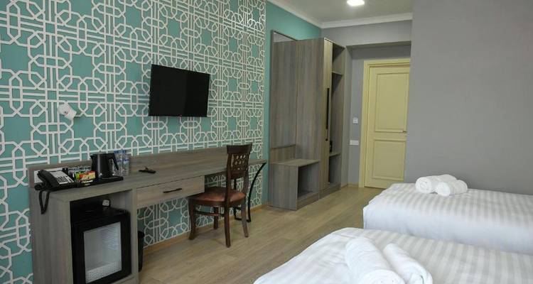 Chambre d'hôtel moderne avec papier peint à motifs et lits jumeaux.