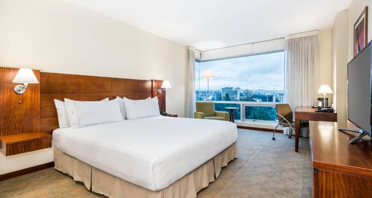Una habitación de hotel moderna con una cama grande y vista a la ciudad.