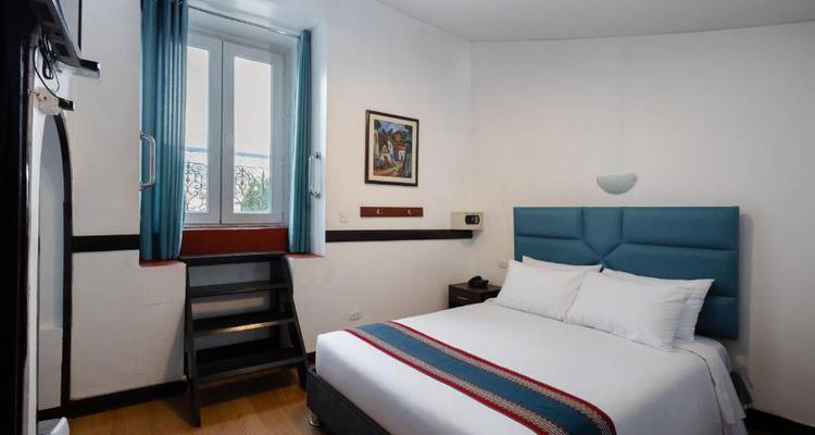 Habitación de hotel sencilla con cama doble y ventana pequeña.