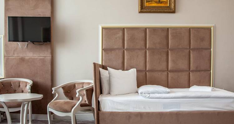 Ein Hotelzimmer-Interieur mit einem Einzelbett, zwei Stühlen und einem Fernseher.
