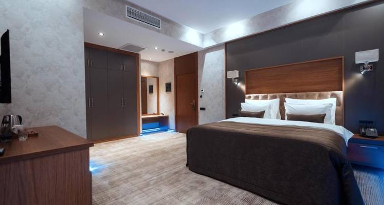 Modernes Hotelzimmer mit einem großen Bett und dunklen Holzmöbeln.