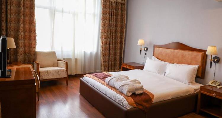 Hotelzimmer mit einem Bett und klassischen Holzmöbeln.