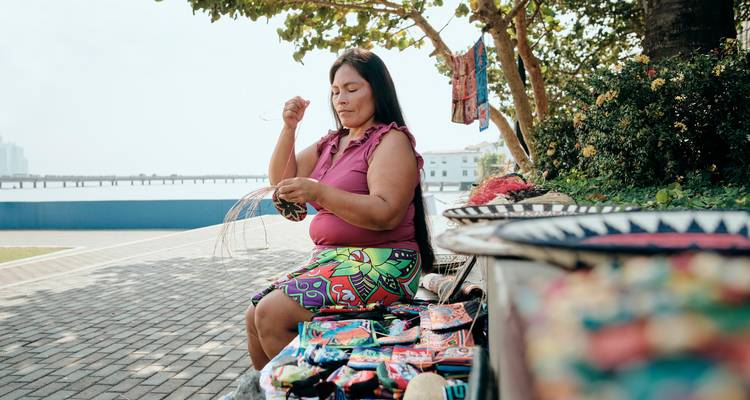 Femme tissant de l'artisanat au bord de la rue.