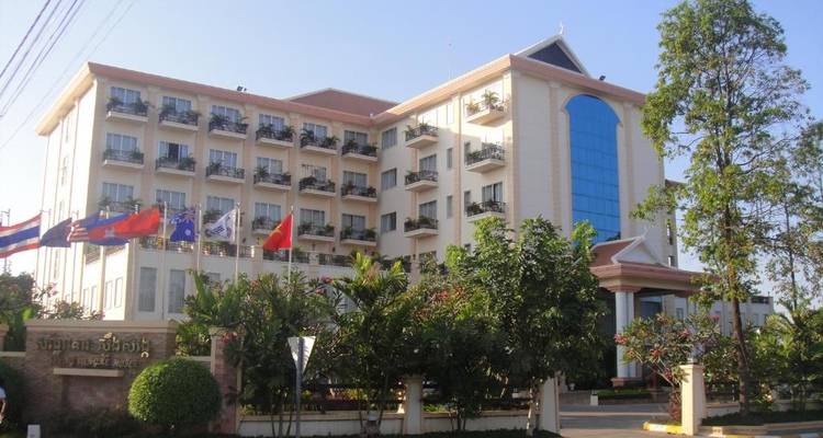 Een hotelgebouw met meerdere balkons en vlaggen bij de ingang.