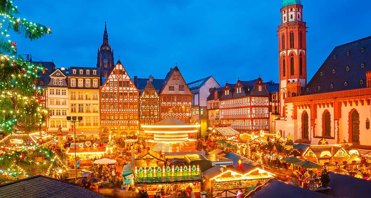 Scène vibrante de marché de Noël avec des étals illuminés and bâtiments historiques.