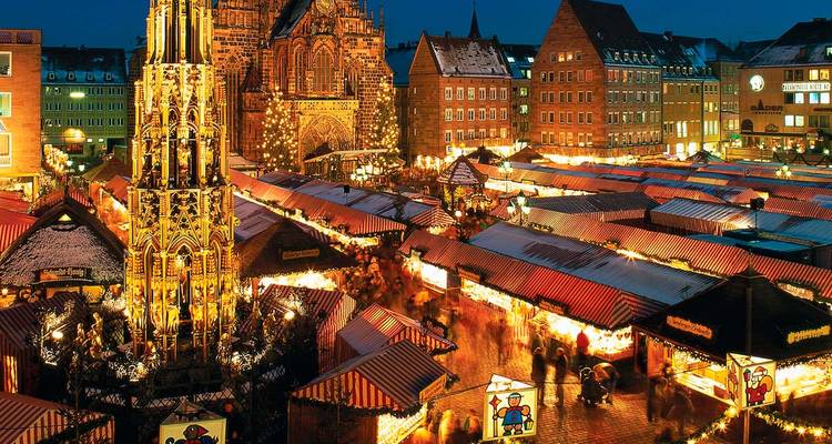 A vibrant Christmas market at night with stalls and a historic church.