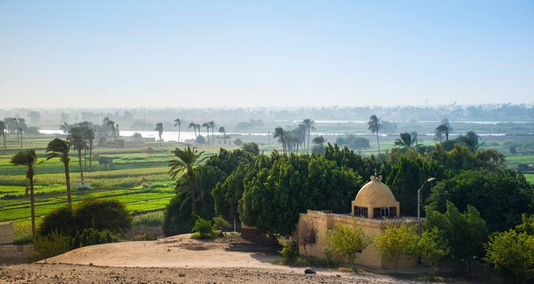 Vista del campo con vegetación y pequeño edificio