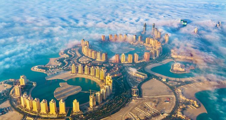 Vista aérea de islas artificiales con edificios parcialmente cubiertos por niebla.