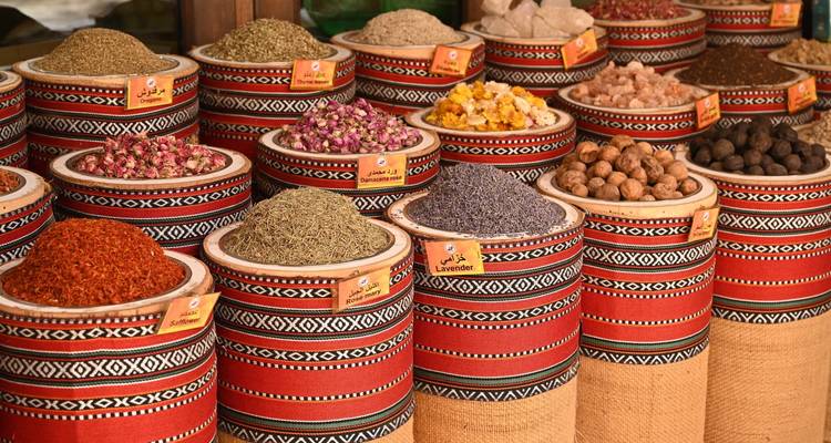 Bunte Gewürze ausgestellt auf einem Markt mit roten und gemusterten Körben.