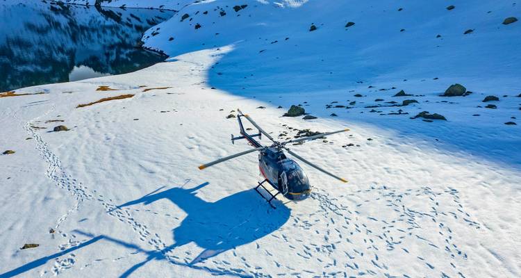 Vue aérienne montrant un hélicoptère sur une surface enneigée près d'un lac.