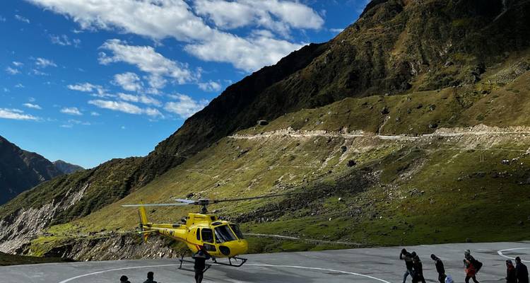 Un hélicoptère jaune a atterri sur un héliport dans une région montagneuse.