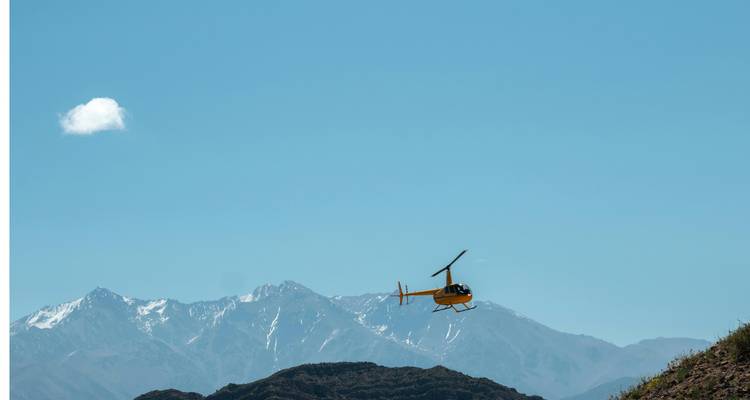 Hélicoptère volant au-dessus d'un paysage montagneux avec un ciel bleu.