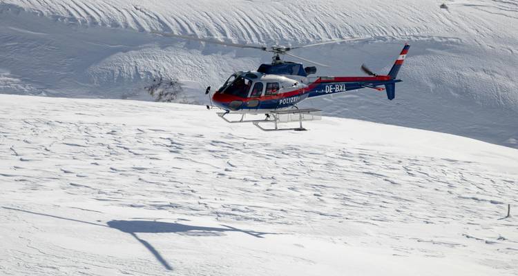 Hélicoptère descendant sur un paysage enneigé dans une zone montagneuse.