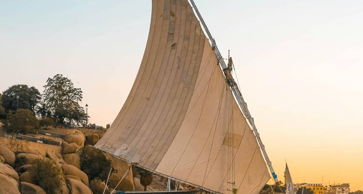 Grote zeilboot met decoratieve zeilen bij zonsondergang.