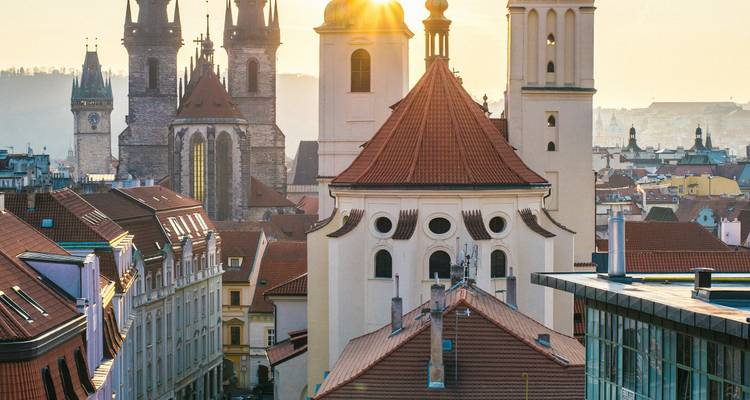 Dächer in Prag mit sonnenbeschienenen Kuppeln und Türmen.
