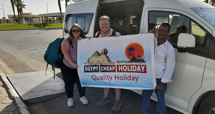 Groupe de touristes posant avec une bannière de voyage près d'un van.