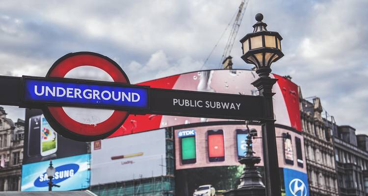 London Underground Schild mit Straße im Hintergrund.