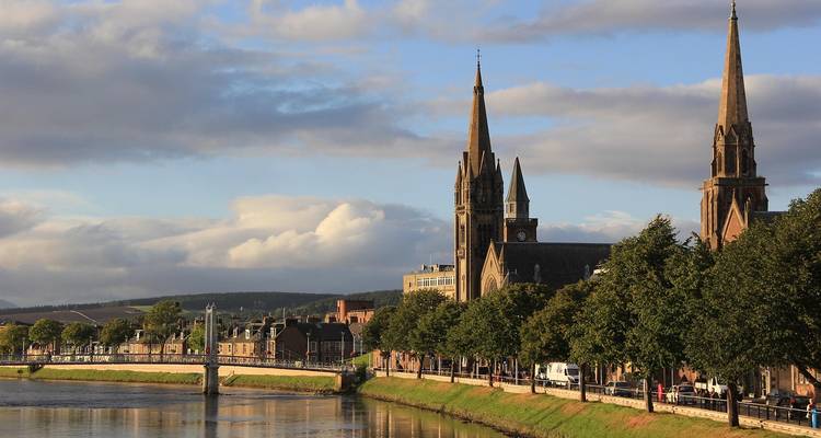 Kirchturmspitzen entlang eines Flussufers.