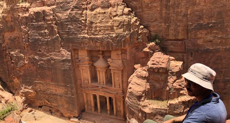 Hombre sentado al borde contemplando la antigua ciudad de Petra.