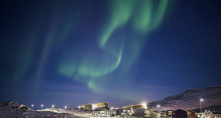 Northern lights over a Greenlandic town with modern buildings.