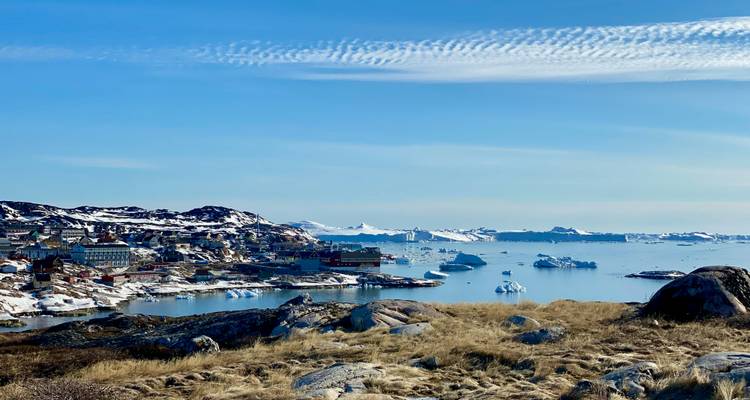Groenlandse kustplaats met ijsbergen in een fjord.