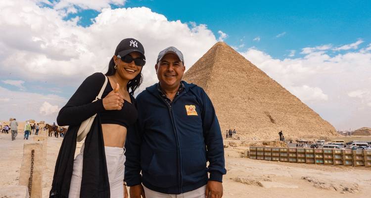 Dos personas posando con la Gran Pirámide de Giza al fondo.