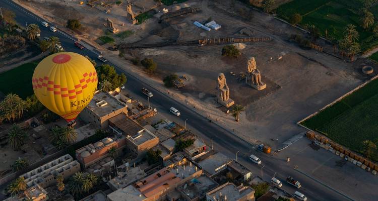 Globo aerostático volando sobre un sitio arqueológico con ruinas antiguas.