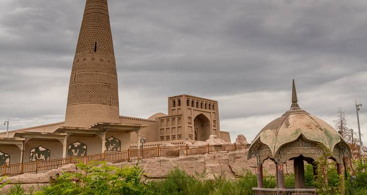 Minaret et mausolée avec un ciel nuageux en arrière-plan.