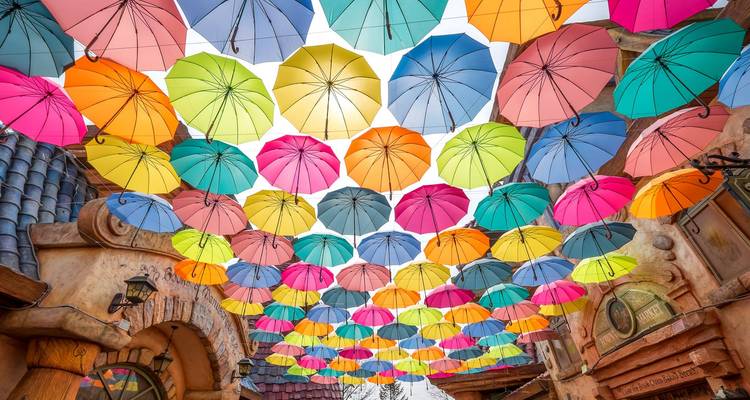 Des parapluies colorés suspendus au-dessus dans un marché ou un cadre de festival.