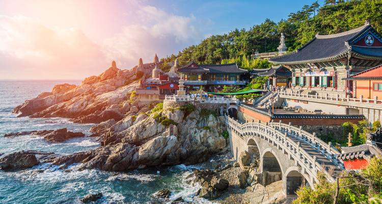 Temple de Haeundae au bord de mer avec une côte rocheuse et un ciel bleu.