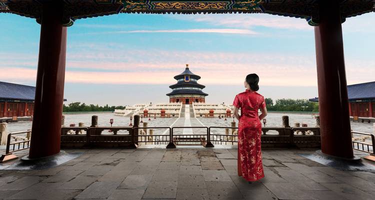 Femme en tenue traditionnelle face à un temple historique au lever du soleil.
