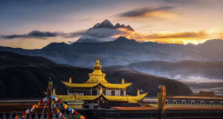 Gouden klooster met besneeuwde bergen in de verte.