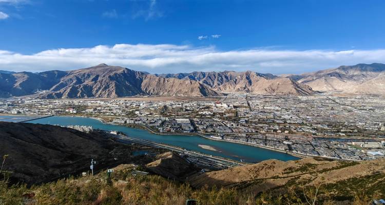 Luftaufnahme der Stadt Lhasa mit Bergen im Hintergrund.