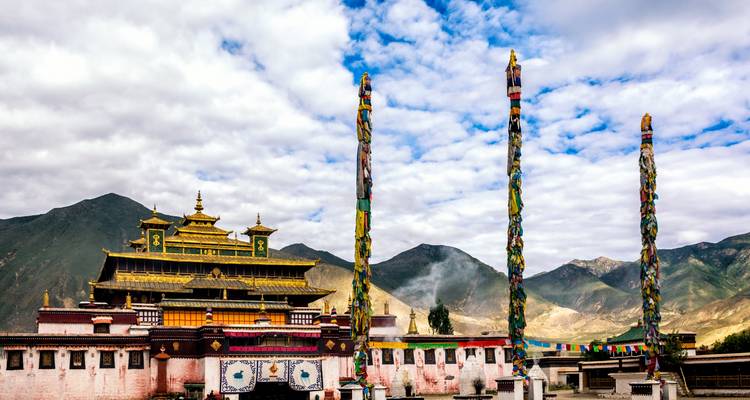 Ein Kloster mit bunten Gebetsfahnen und Bergen.