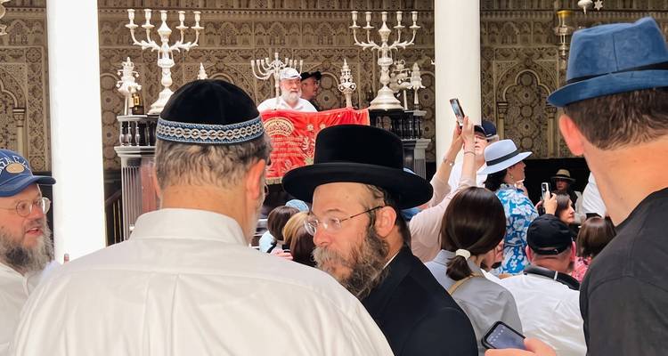 Gemeindemitglieder und Touristen versammeln sich während eines Gottesdienstes in einer reich verzierten Synagoge.