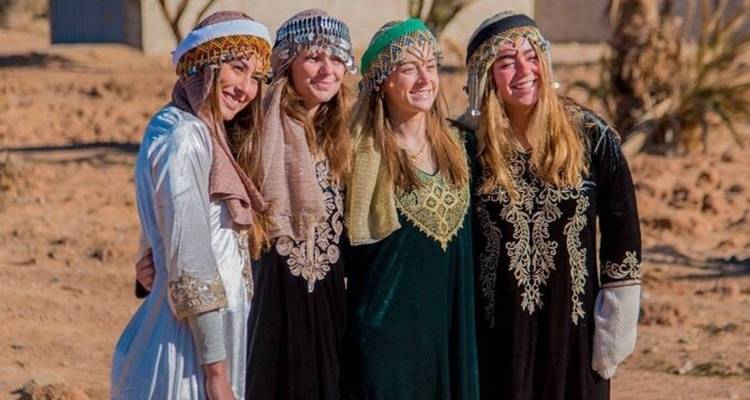 Quatre femmes portant des robes traditionnelles dans le désert.