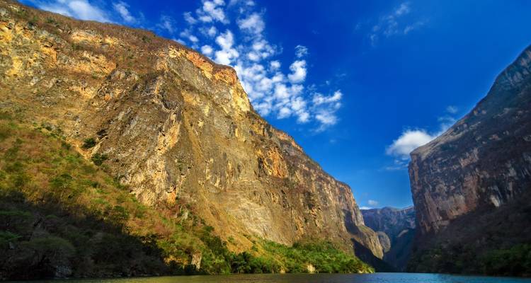 Steile Felswände des Sumidero-Canyons, die sich über dem Grijalva-Fluss unter einem leuchtend blauen Himmel erheben