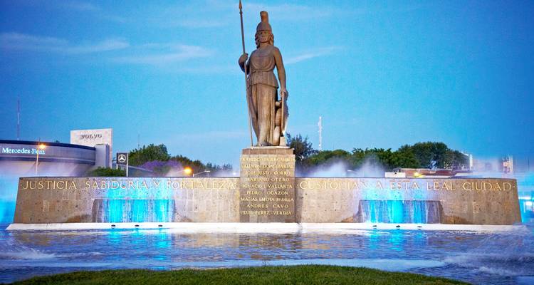 Schemerzicht van Minerva Fontein verlicht met blauwe lichten en mistige waterstralen.