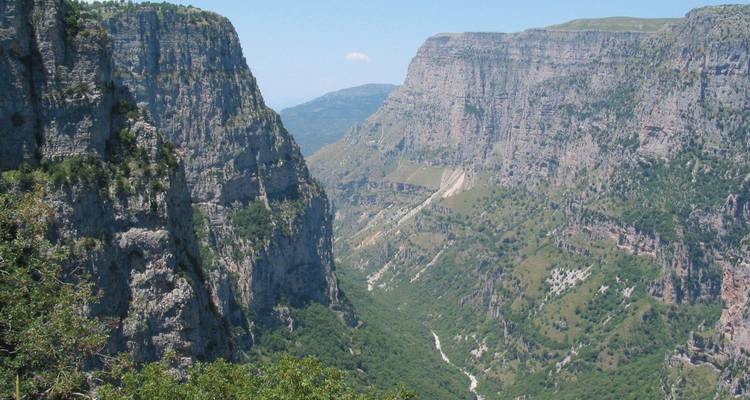 Vue spectaculaire sur les gorges de Vikos avec des falaises calcaires abruptes et une rivière sinueuse loin en contrebas.