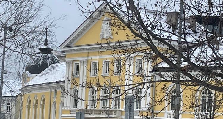 Yellow building with snow-covered roof in a winter setting.