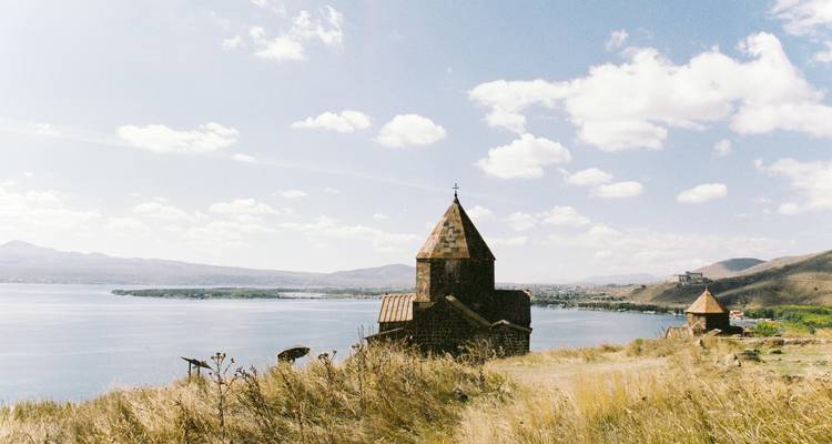 Église surplombant un lac avec des collines en arrière-plan.