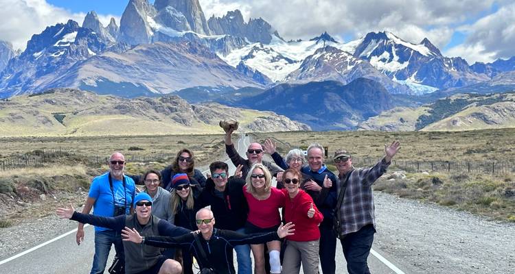 Grupo lleno de energía posando en una ruta con el Cerro Fitz Roy y picos nevados que se alzan dramáticamente detrás.